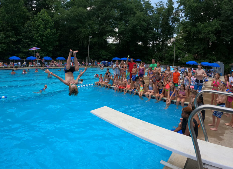Child flipping off of a diving board at Fair Blue Swim Club