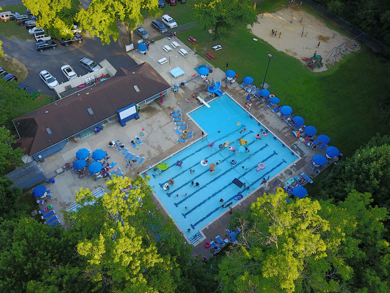 Drone image of Fair Blue Swim Club in the afternoon looking down at the pool and grounds
